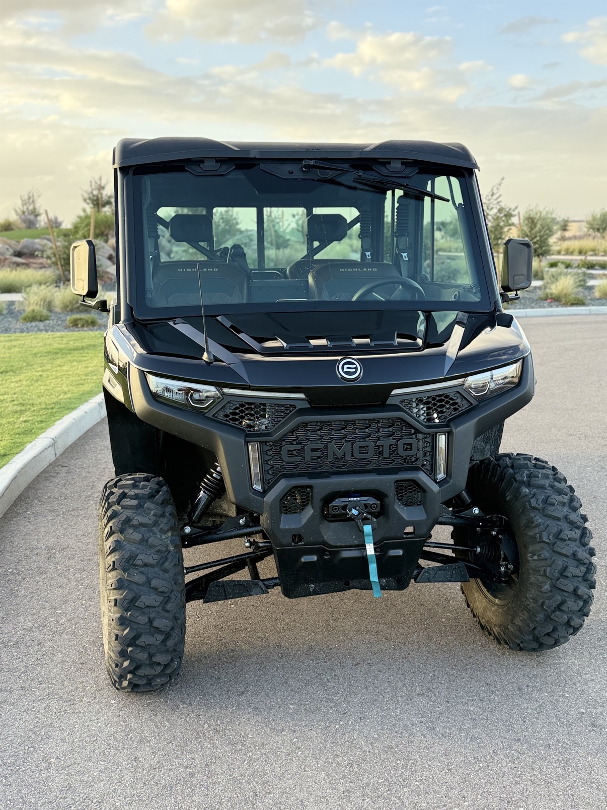 Front view of the CFMOTO U10 Pro XL Highland at sunset, headlights on